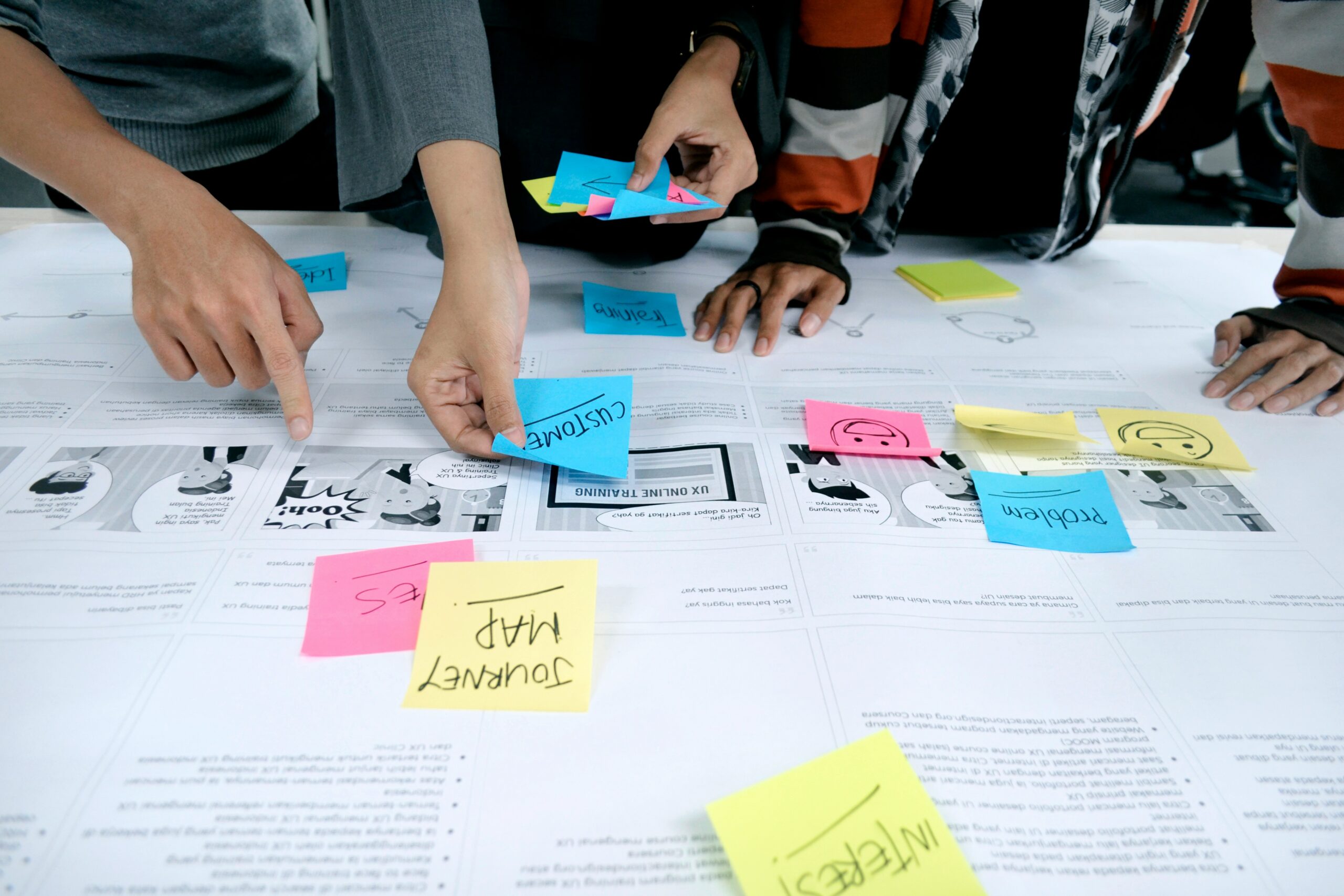 Mehrere Personen lehnen sich an einen Tisch an, auf dem Sticky Notes angeheftet werden.