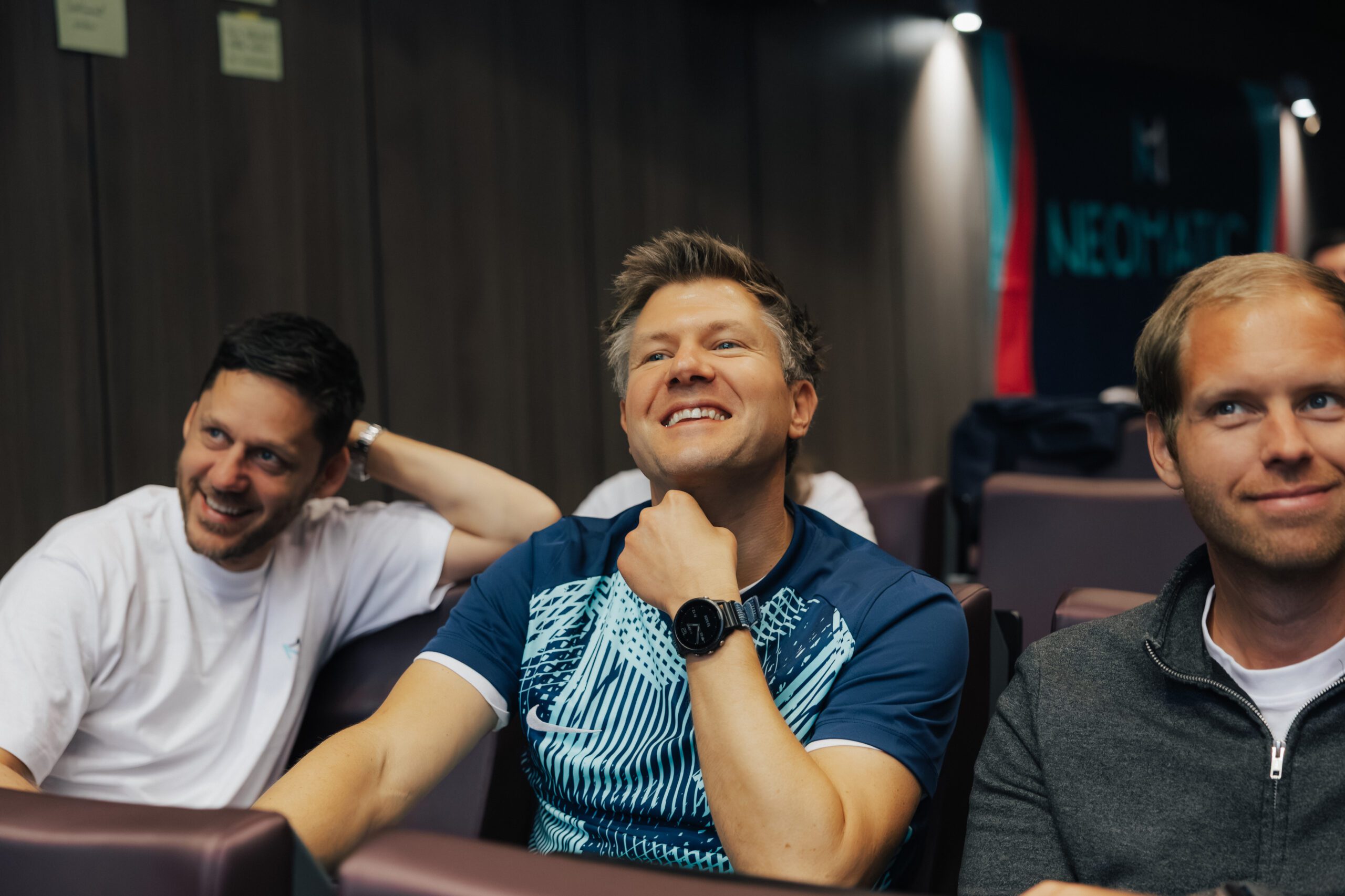 NEO.cation 2025 Drei Personen sitzen in einem Meetingraum und lachen
